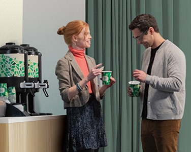 Two colleagues speak next to Chameleon self-serve coffee station