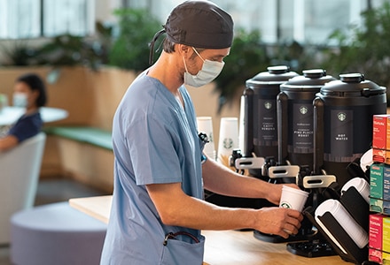 Doctor Pouring Cup of Starbucks Coffee in Hospital Café