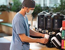 Doctor Pouring Cup of Starbucks Coffee in Hospital Café