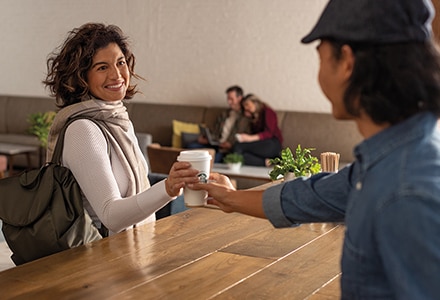 Barista Handing Starbucks Coffee Cup to Woman in Hotel