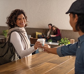 Barista Handing Starbucks Coffee Cup to Woman in Hotel